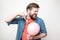 Bearded man is about to burst a balloon with a fork and bared his teeth in fear. Fun or stress concept