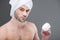 bearded man in towel holding face cream,