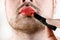 Bearded Man Transvestite Makes Up Lips with Lipstick