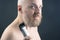 Bearded man with trimmer to adjust beard in hand