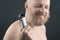 Bearded man with trimmer to adjust beard in hand