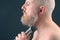 Bearded man with trimmer to adjust beard in hand