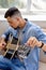 bearded man tuning acoustic guitar at home, Young guitarist fixing tuning pegs close-up