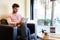 Bearded man using a tablet sitting in a sofa next to a window in a cafe