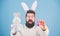Bearded man wear bunny ears. Egg hunt. Look what i found. Hipster cute bunny blue background. Easter bunny. My precious