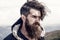 Bearded man on windy mountain top on natural cloudy sky