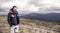 Bearded man on windy mountain top on natural cloudy sky