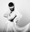 Bearded man in a woman\'s wedding dress on her naked body, holding a flower. funny bearded bride, black and white