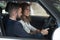 Bearded manager sitting with woman in car and showing cabin.