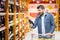 Bearded mature man in supermarket choosing red wine bottle from shelves