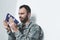 Bearded military man crying while sitting by wall and holding usa national flag