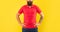 Bearded mustached man crop view standing in red tshirt with arms akimbo yellow background, beard