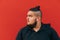 Bearded overweight man in wireless headphones looking to the side, close portrait on red background