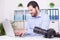 Bearded photographer at his office with laptop and camera