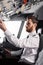 bearded pilot reaching overhead panel while