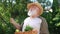 Bearded positive gardener smelling fresh greenery standing in summer spring garden outdoors. Senior Caucasian farmer