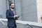 Bearded professional man broker standing outdoor while holding digital tablet in his hands. Modern businessman thinking overview