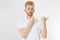 Bearded red-haired smile man in white tshirt pointed to blank background copy space isolated over white