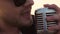 bearded rock star singer with glasses sing expressive song in retro microphone. Extreme close up face man with stubble