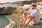 Bearded romantic male traveler in a hat and glasses meets the dawn on the shore of the bay