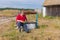 Bearded senior man sitting at country draw-well