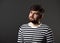 Bearded smiling emotional man in casual striped t-shirt on grey