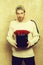 Bearded smiling man holds red rose box on textured wall