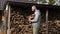 Bearded strong man standing with an armful of logs and put them together in the pantry with logs for fire heat