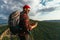 A bearded traveler with a backpack on the top of a mountain. Portrait of a traveler in a red cap and sunglasses.