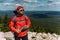 A bearded traveler with a backpack on the top of a mountain. Portrait of a traveler in a red cap and sunglasses.