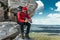 A bearded traveler with a backpack on top of a mountain. Portrait of a traveler in red clothes and sunglasses.