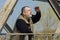 bearded Ukrainian  senior man standing on an metal pedestrian bridge and looking out  at the distance