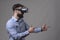 Bearded young adult man wearing vr headset with finger gun gesture simulate shooting augmented reality weapon