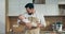 Bearded young father in apron standing at wooden table in modern kitchen holding newborn happy son on hands playing with