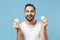 Bearded young man 20s years old in white shirt hold in hand cotton pad isolated on blue pastel wall background, studio