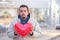 Bearded young man with closed eyes and ready to kiss holding a red heart shape air ballon in the city steet. Urban romance