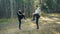 Bearded young man is doing sports in park with his girlfriend stretching legs doing warm-up smiling and talking