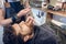 Bearded young man ready for shaving in the hair salon of a skilled barber