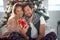 Beardy guy looking with smile wrapped present holding in hand with beautiful blonde leaned on his shoulder