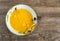 Beaten egg yolks in the plate on old wooden background, top view