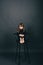 Beatiful little girl with long hair in a black clothes and barefoot sits on a chair in the studio