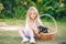 Beatiful little girl with long hair with puppies in a basket on green grass