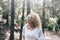 Beauiful blonde curly woman enjoy the outdoor leisure activity in the forest - People in the wood trees nature with defocused