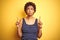 Beauitul african american woman wearing summer t-shirt over isolated yellow background Pointing up looking sad and upset,