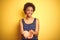 Beauitul african american woman wearing summer t-shirt over isolated yellow background Smiling with hands palms together receiving