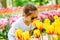 Beauriful dutch girl smelling tulip flower on tulip fields. Child in tulip flower field in Holland. Kid in magical Netherlands