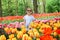 Beauriful dutch girl smelling tulip flower on tulip fields. Child in tulip flower field in Holland. Kid in magical Netherlands