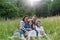 Beautfiul young family sitting in grass at meadow, enjoying together time.