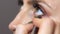 The beautician applies eyeliner to the lower eyelid of the girl`s eye. Close up video of professional makeup artist with soft thin