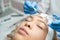 Beautician applying beauty oil mask on face skin using brush in spa salon. Woman on peeling procedure at cosmetology salon.